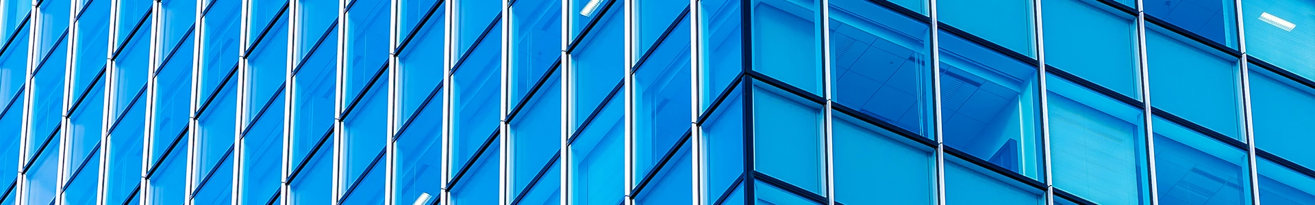 Close‑up view of modern glass office building facade with blue reflective windows.