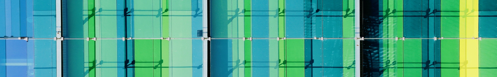 Abstract green and blue glass building facade with grid patterns and light reflections.