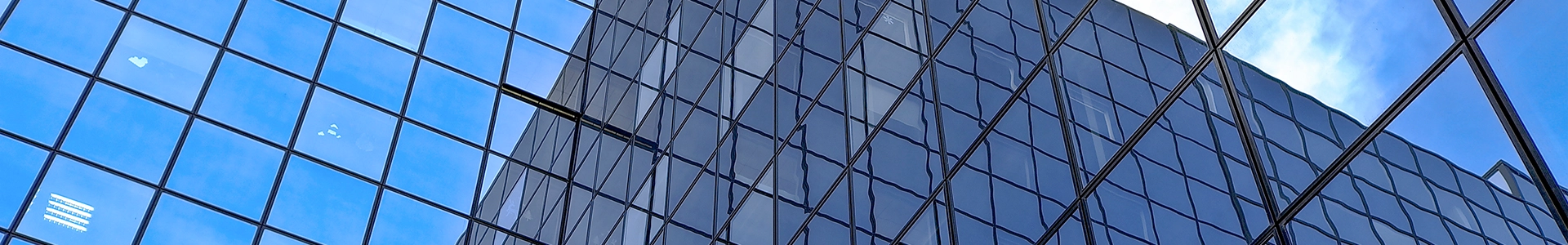 Close-up view of a modern glass office building with reflective blue windows forming geometric patterns.