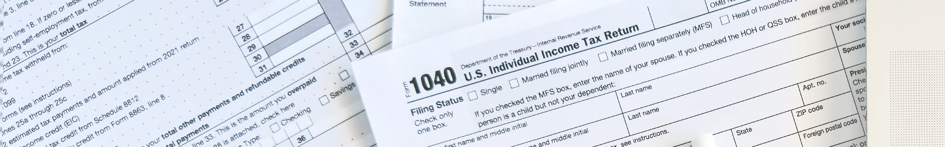 Close-up of U.S. tax forms, including a 1040 individual income tax return, spread out on a desk.