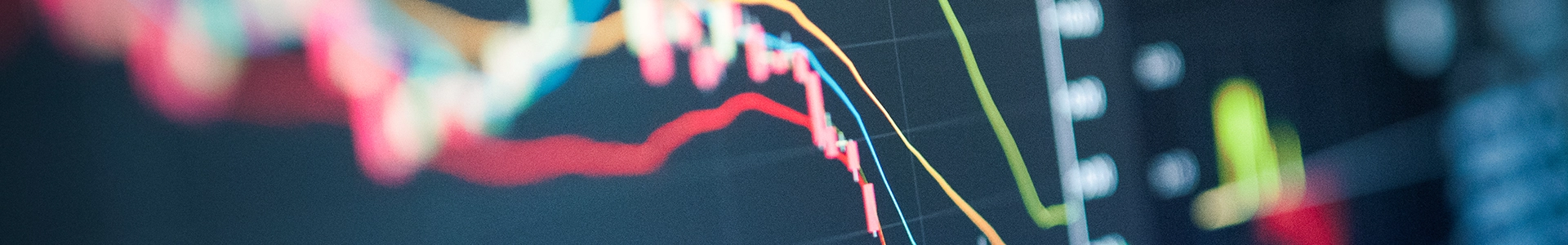 Close-up of a digital screen displaying multicolored declining financial line graphs and data points.