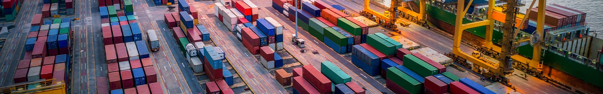 Aerial view of a busy shipping port with rows of colorful cargo containers and cranes loading vessels.