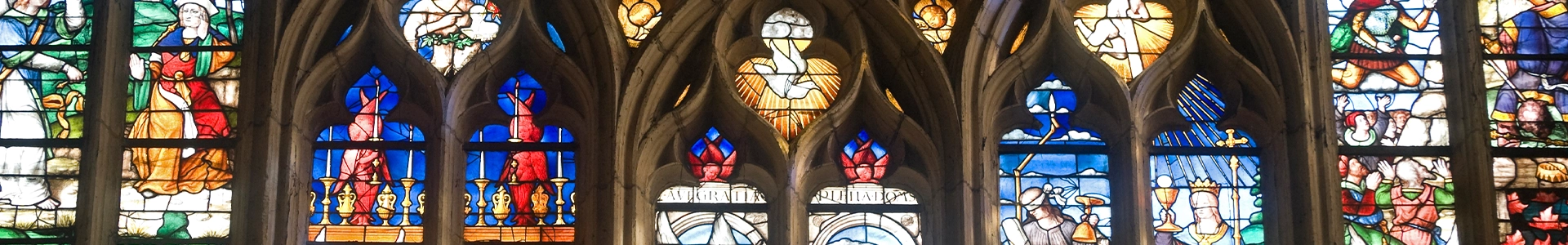 Colorful stained‑glass windows depicting various figures and scenes framed by ornate stone arches.