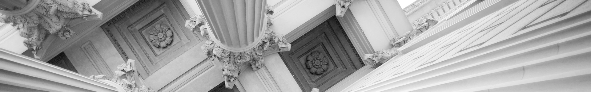 Upward view of ornate classical columns and detailed architectural carvings on a grand stone building.