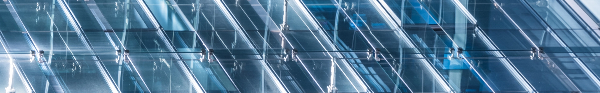 Abstract close‑up of modern glass building facade with reflective panels and linear architectural details.