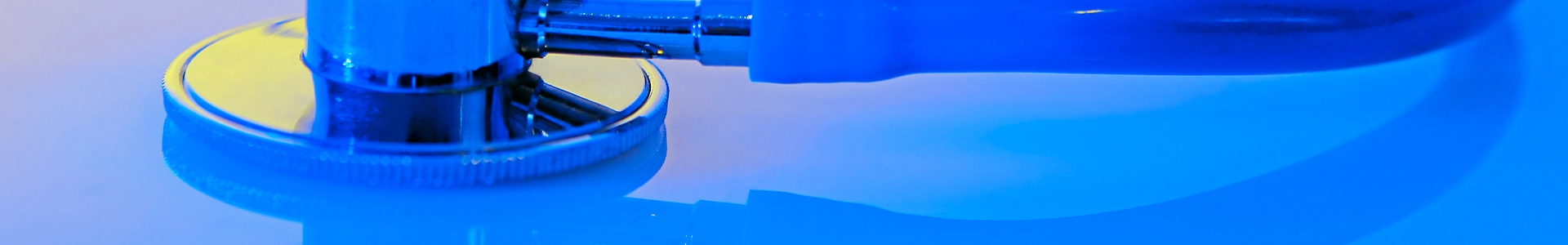 Close-up of a stethoscope resting on a reflective surface under bright lighting.