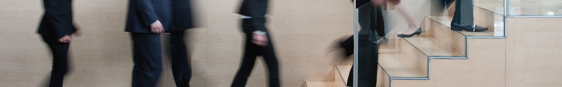 Business professionals walking through a modern office space and ascending stairs.