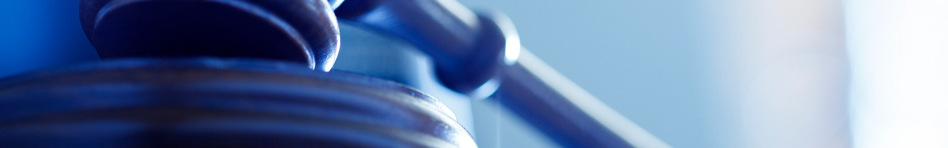 Close-up of a wooden judge’s gavel resting on a sounding block.