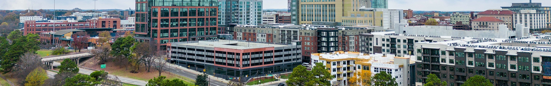 Panoramic view of downtown Durham featuring modern office buildings, residential complexes, and surrounding greenery.