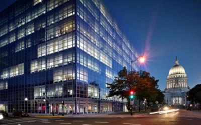 Evening view of the Michael Best Madison office building with glass exterior, overlooking the illuminated Wisconsin State Capitol.