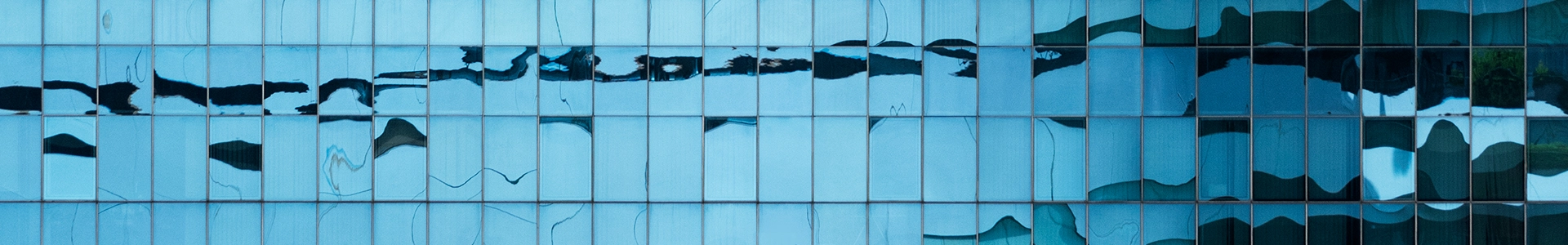 Abstract blue glass building facade with reflective panels and flowing patterns.