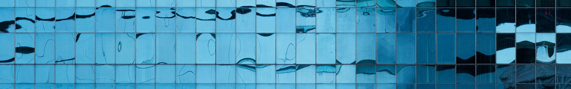 Abstract blue glass building facade with reflective panels and flowing patterns.