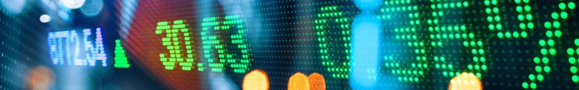 Digital stock market board displaying various colorful numbers and bokeh lights.